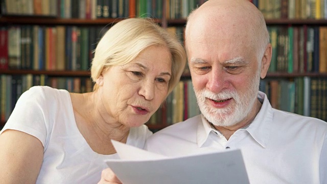 一对老年夫妇正在阅读投资财务文件。有纳税报告的退休退休人员家属视频下载