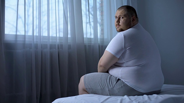 悲伤沉重的男人坐在家里的床上，健康问题，抑郁，不安视频素材