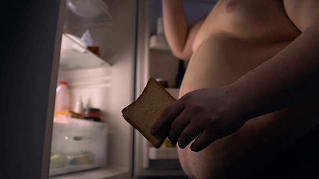 嗜吃快餐的胖子在冰箱旁边吃三明治喝啤酒视频下载