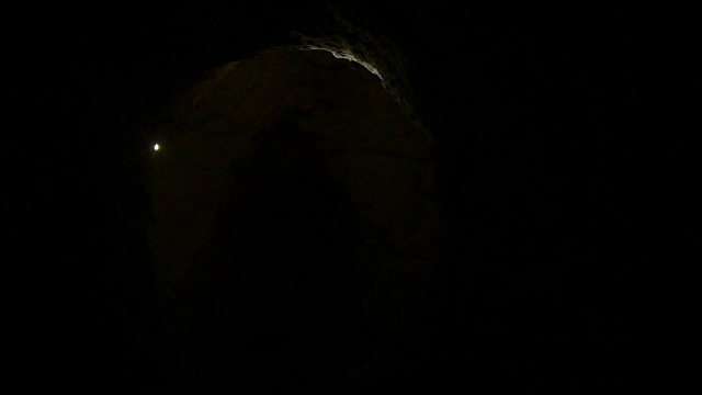 年轻的女性徒步旅行者拿着手电筒探索黑暗的洞穴视频素材