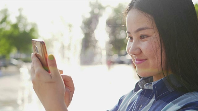 年轻漂亮的亚洲女孩享受她的一天在城市，而发送短信与她的智能手机视频素材