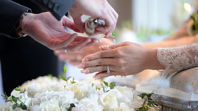 泰国婚礼，双手向新郎新娘的手带中注入祝福水视频下载