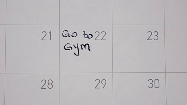 年轻的少女计划去健身房在日历上标记一天，用黑色的钢笔写提醒视频素材