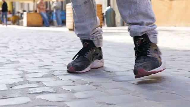 一个穿着运动鞋的男人沿着人行道走视频下载