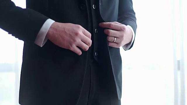 新郎穿着黑色西装，扣着上衣的扣子。视频下载