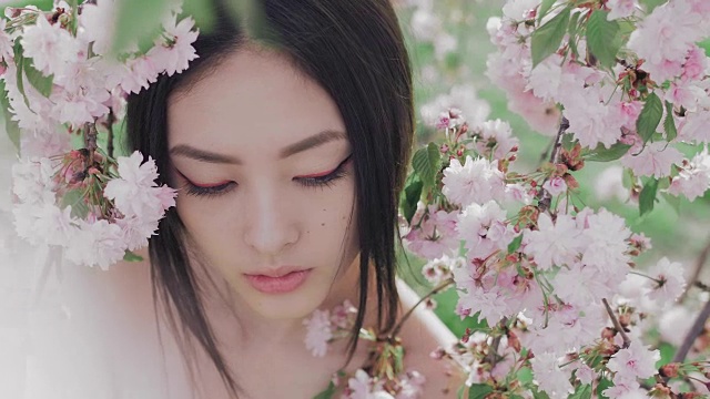 一个美丽的亚洲女孩的肖像户外对着春花树视频下载