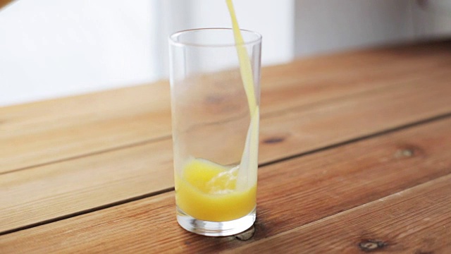 橙汁倒进木桌上的玻璃杯里视频下载