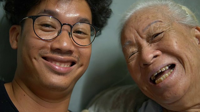 年轻快乐的亚洲人与奶奶对着镜头微笑。视频素材