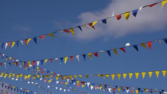 彩色三角旗为党在蓝天的背景上迎风飘扬。背景板，色度键视频背景视频下载