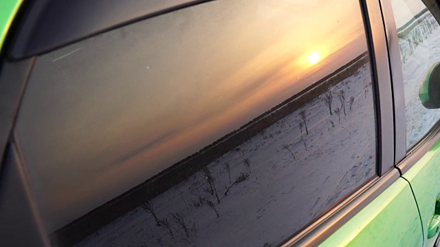 夕阳的余晖映在车窗上。美丽的日落在冬天的田野4k视频下载