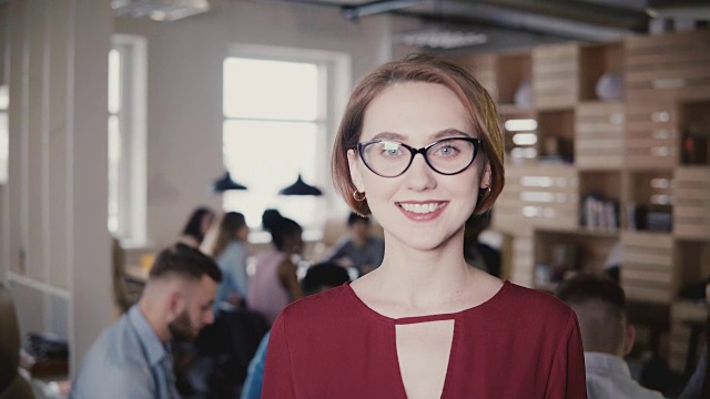 快乐自信的欧洲年轻女商人对着镜头微笑。自信的女老板在办公室背景摆4K视频素材
