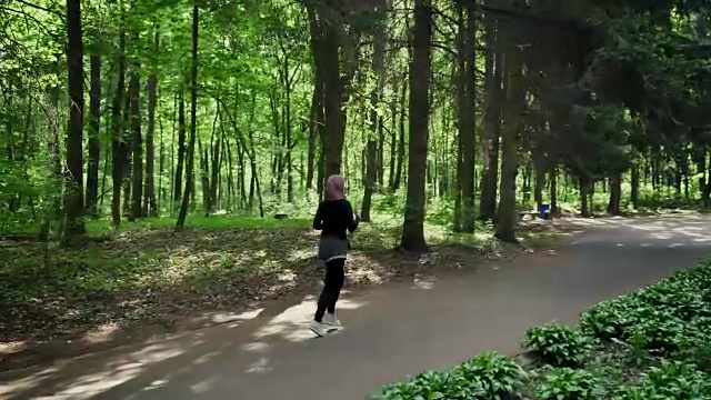 年轻的运动女孩戴着头巾跑步，在绿色公园慢跑，后视图50帧/秒视频下载