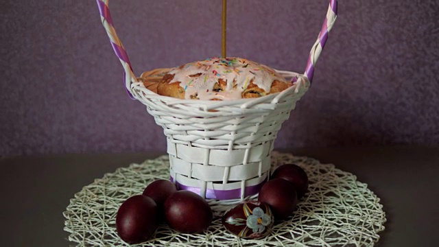 节日的复活节蛋糕与蜡烛在柳条篮子和一些颜色的鸡蛋下面视频下载