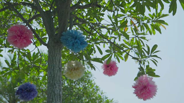 五颜六色的装饰花在花园里的树上摇摆。视频下载
