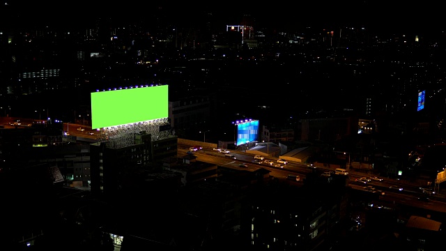 广告牌绿色屏幕与城市夜间交通灯背景。泰国曼谷。4 k决议。视频素材