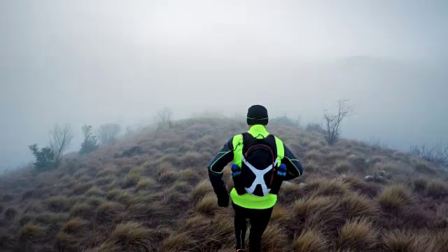 一个寒冷的早晨，一名男性跑步者在长满草的山路上跑步视频下载