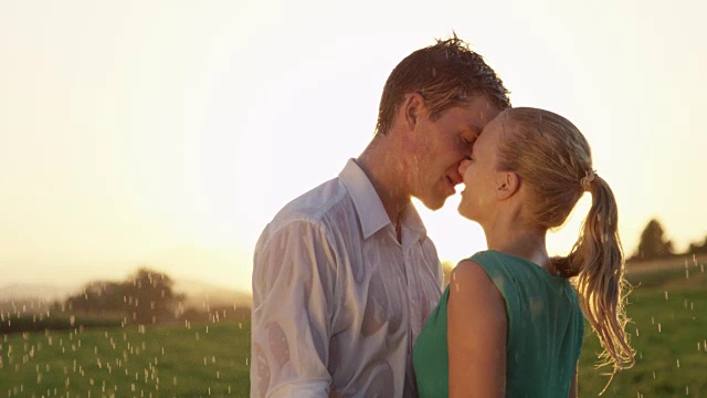 慢镜头:欢快的男人和女人在一次春雨中热吻。视频素材