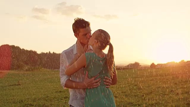近距离镜头:年轻的恋人在雨中的绿色乡村热烈接吻视频素材