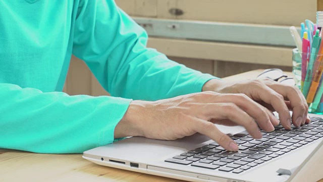 绿色长袖t恤商人打字笔记本电脑在家庭办公室。交流通过网络视频素材
