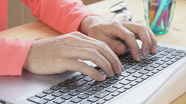 橙色长袖t恤商人打字笔记本电脑在家庭办公室近距离观察视频素材