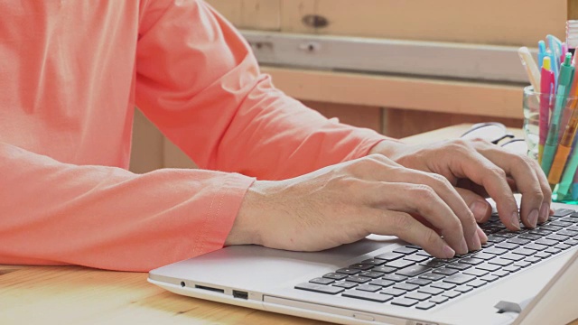橙色长袖t恤商人打字笔记本电脑在家庭办公室。利用互联网工作和交流视频素材