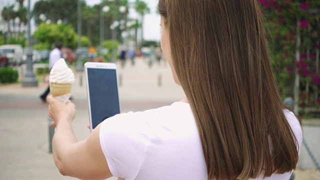 一个女人正在给冰淇淋蛋卷拍照。青少年用手机拍摄冰淇淋的慢动作视频素材