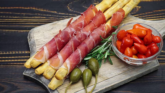 意大利grissini配意大利熏火腿，酸豆和胡椒在木砧板上视频下载