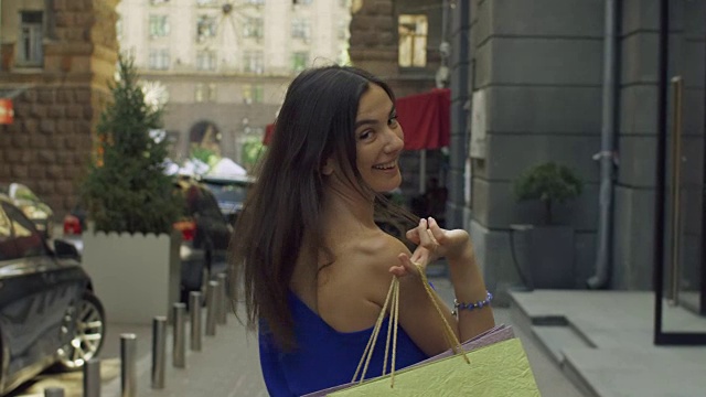 优雅的女人拿着购物袋走在街上视频素材