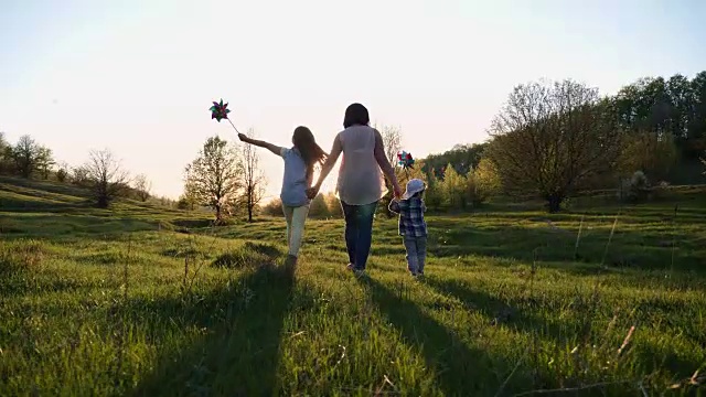 妈妈带着两个孩子在日落时分散步视频素材