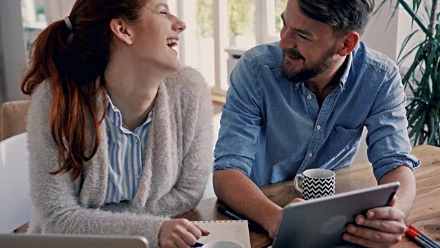 年轻的幸福夫妇使用数码平板电脑，享受在家里的咖啡时间。视频素材