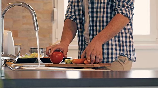 一个面目全非的男人在厨房做饭时洗菜。视频素材