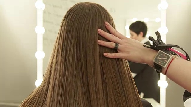 美发师在美容院为女士梳头前镜梳理长发。在美容院近距离观察女性发型视频下载