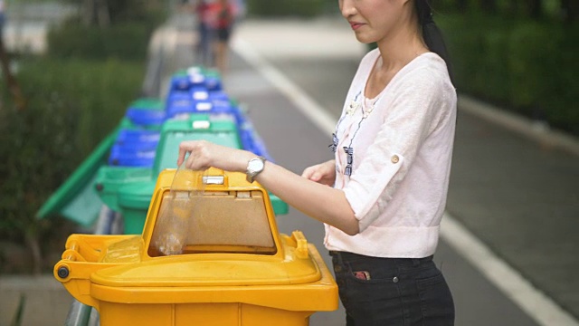 亚洲妇女把塑料瓶扔进垃圾桶垃圾视频素材