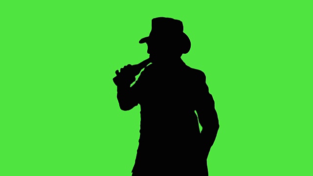 一个戴着帽子，手里拿着酒瓶的酷男正在喝啤酒，享受着，有节奏地移动着视频素材