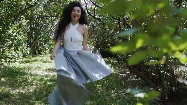 美丽的深褐色的蓝色连衣裙走在花园慢动作视频下载