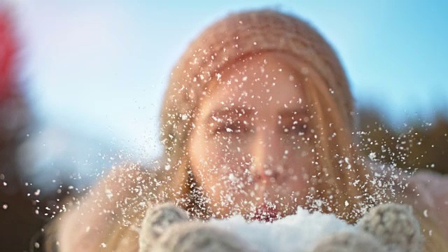 SLO MO美丽的年轻女子吹雪从她的手中进入相机视频素材
