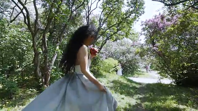 年轻的笑着的女人和红苹果跑过阳光灿烂的花园，慢镜头视频下载