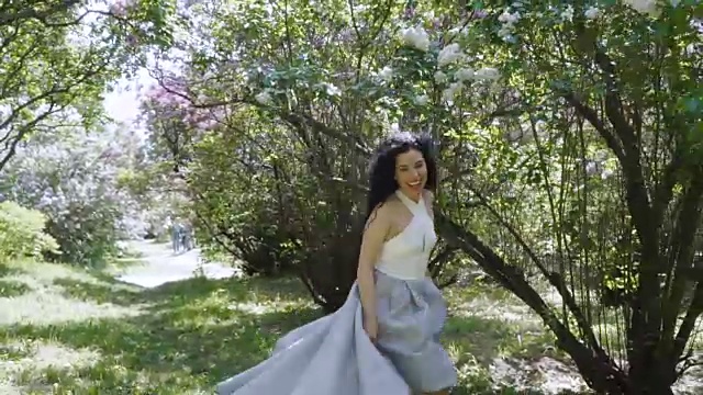 美丽的笑着褐发女人跑在镜头上通过一个夏天的花园视频下载