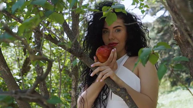 迷人的女子与红苹果享受水果的气味和微笑的镜头视频下载
