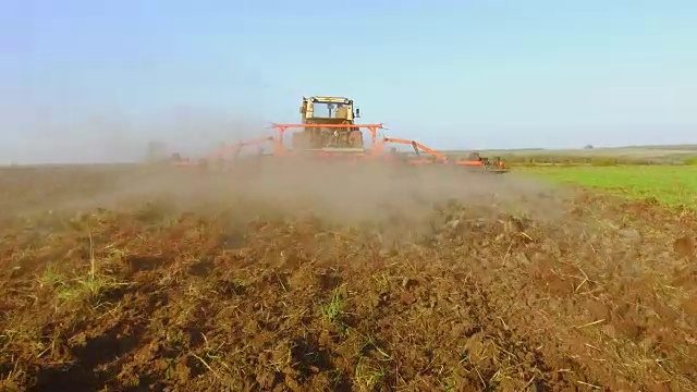 农民在拖拉机犁地俄罗斯稳定摄像机运动农业土壤准备土地与苗床中耕作为生活方式的一部分，在早春季节的农业工作在农田的播种活动。农业的概念视频素材