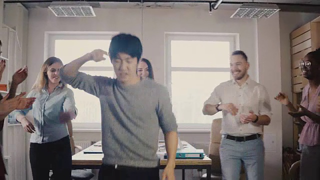 快乐的亚洲年轻商人在办公室聚会上跳舞。一名日本员工与同事用4K庆祝胜利视频素材