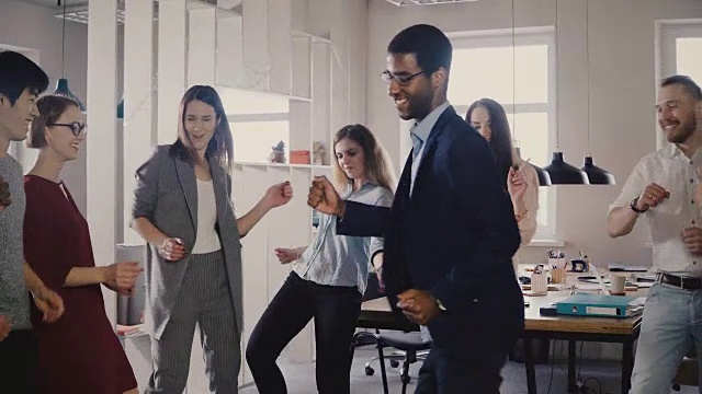 快乐的非裔美国高管与同事在一个非正式的办公室聚会上跳舞，庆祝商业成就4K视频素材