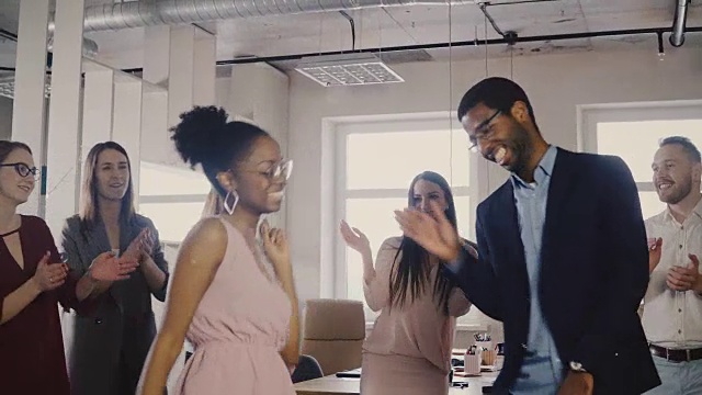 两个非裔美国同事在一个非正式的办公室聚会上一起跳舞。不同的朋友分享快乐的时间在工作4K视频下载