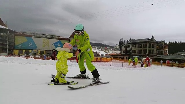 一个教练教一个小女孩如何滑雪。视频素材
