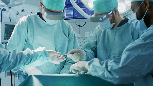 戴着增强现实眼镜的外科医生在高科技医院进行最先进的混合现实手术。在手术室工作的医生和助手。视频素材