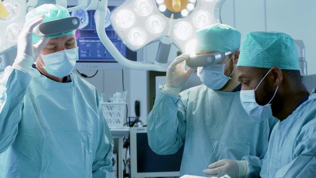 在高科技医院，外科医生戴上增强现实眼镜进行最先进的手术。在手术室工作的医生和助手。视频素材