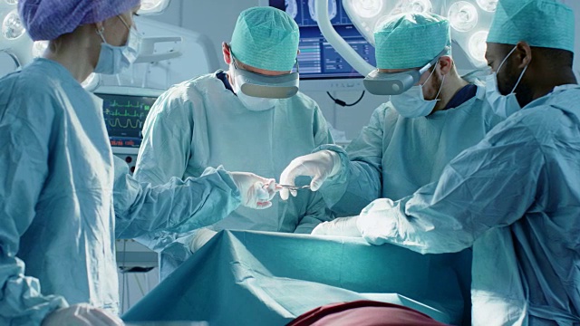 外科医生戴着虚拟现实眼镜在技术先进的医院进行最先进的手术。在手术室工作的医生和助手。视频素材