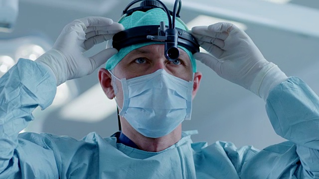 在医院手术室里，专业外科医生打开外科手电筒，看着摄像机。视频下载