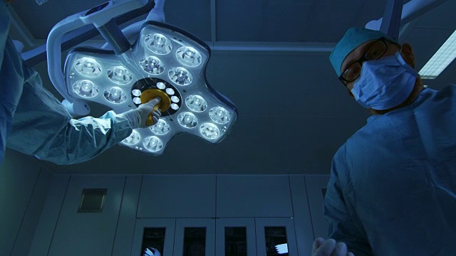 低角度拍摄入睡POV患者视角:两名专业外科医生打开手术灯，麻醉师戴上麻醉口罩。视频素材