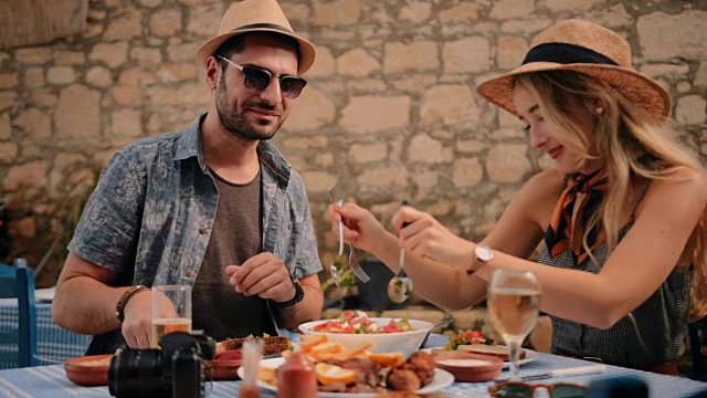 年轻的游客夫妇在传统的希腊餐厅吃有趣的视频素材